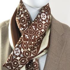 "Large Silk Twill Shawl. Brown interlocking pattern on cream Silk. Length is 70 inches, width is approx. 26\". * Digitally printed original design * 100% silk twill. * Approx. 70\" x 26\". * Machine hemmed on long edges, hand-fringed on short edges * Dry clean only * Ironing is fine, press cloth recommended to prevent staining * Arrives packed in an elegant gift-box" Cream Silk Scarf For Formal Occasions, Formal Beige Silk Scarf, Classic Brown Silk Scarf, Beige Silk Shawl Scarf, Mens Silk Scarf, Interlocking Pattern, Mens Silk Scarves, Long Edges, Meditation Shawl