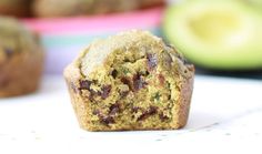 a muffin sitting on top of a table next to an avocado