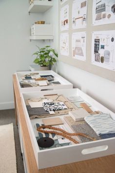 two drawers with pictures on the wall above them and a plant in front of it