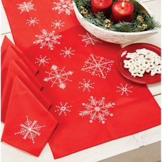 red napkins with white snowflakes on them next to candles and christmas decorations