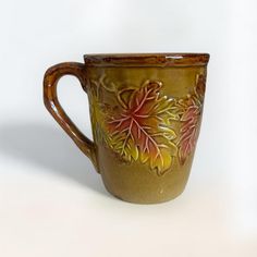 a coffee cup with leaves painted on the outside and inside, sitting on a white surface