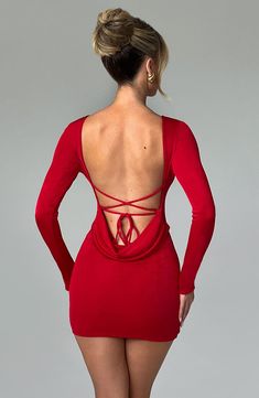 a woman in a red dress with her back to the camera and hands on hips