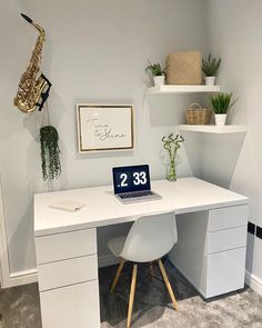 a white desk topped with a laptop computer sitting next to a wall mounted planter