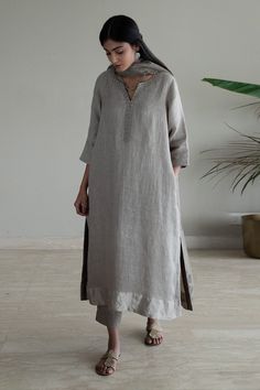 Taupe kurta with woven silver border on sleeve hem, placket and neckline in stripe pattern. Paired with pant.
Components: 2
Pattern: Woven
Type Of Work: Stripe
Neckline: Notched
Sleeve Type: Three quarter
Fabric: Kurta: Handwoven Linen, Pant: Cotton, Lining: Shantoon
Color: Grey
Other Details: 
Side pockets
Attached lining
Note: Dupatta worn by the model is not for sale
Disclaimer: The fabric, color and texture of the final garment might have slight variations from the studio images and we use o Linen Kurti Design, Shorshe Clothing, Linen Suits Women, Studio Images, A Line Kurti, New Kurti Designs, Kurta Patterns, Indian Designer Suits, Simple Kurta Designs