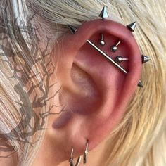 a close up of a person wearing ear piercings with spikes on their ears and behind the ear