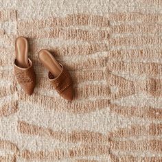 a pair of brown slippers sitting on top of a carpet