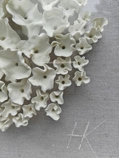 some white flowers sitting on top of a gray table cloth with the word k written in it