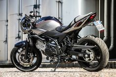 the motorcycle is parked on the side of the road next to a building with metal doors