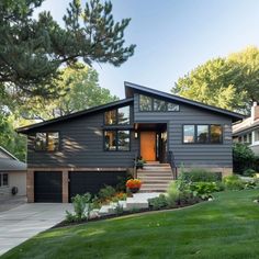 a gray house with lots of windows and grass in front of the entrance to it