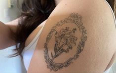 a woman with a tattoo on her arm holding a flower in front of her shoulder