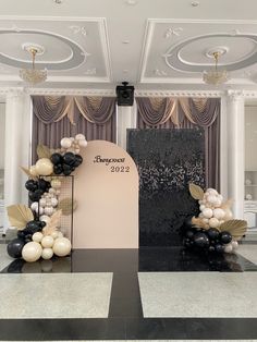 an entrance decorated with balloons and black and white decorations for a wedding or special event