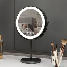 a round mirror sitting on top of a counter next to makeup brushes and other items