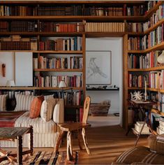 a living room filled with lots of books on top of a wooden shelf next to a couch