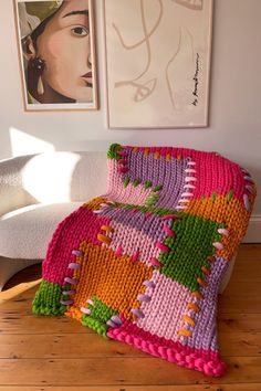 a crocheted blanket sitting on top of a wooden floor next to a white couch