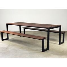 a wooden table and bench sitting next to each other on concrete floor with white wall in background