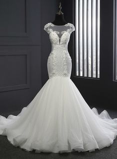 a white wedding dress on display in front of a window