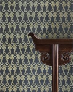 an ornate wooden table against a patterned wallpaper