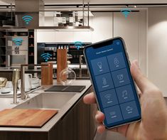 a person holding up a smart phone in a kitchen with wifi connected to the app