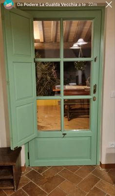 an open green door with the reflection of a table in it's glass window