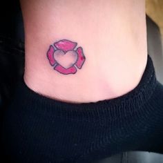 a small heart shaped tattoo on the side of a woman's ankle, with a red ribbon around it