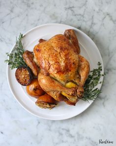 a white plate topped with a roasted chicken and vegetables