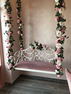 a white iron bed with pink and white flowers on the top, hanging from it's sides