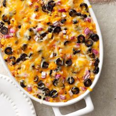 a casserole dish filled with black olives, onions and cheese