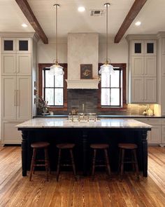 a large kitchen with an island in the middle of it and three stools on each side