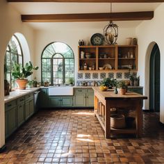 a kitchen with green cabinets and tiled flooring next to an arched window in the wall