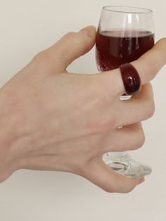 a person holding a wine glass with red liquid in it's left hand,