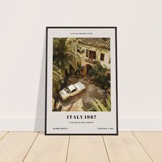 a framed poster with an image of a car parked in front of a house and palm trees