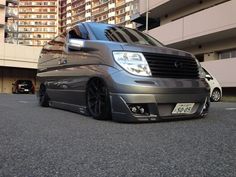 a silver van parked in front of a tall building