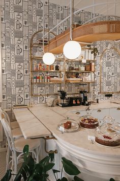 a kitchen counter with plates and cakes on it next to a potted plant in front of a spiral staircase