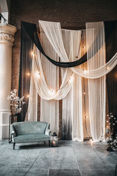 a room decorated with sheer curtains, candles and a blue chair in front of it