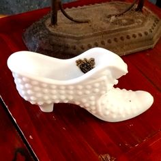 a white vase sitting on top of a table next to a shoe shaped object in the shape of a boot