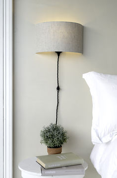 a lamp that is on top of a table next to a book and a potted plant