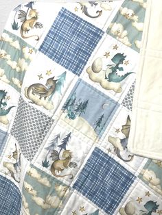 a blue and white quilted blanket with animals on it's sides, sitting on the floor