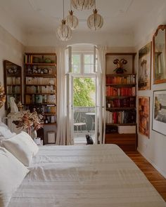 a bed sitting in a bedroom next to a window with lots of books on it