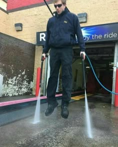 a man with pink hair is holding two hoses in front of a building