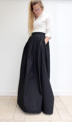 Giselle, our maxi skirt made in pure cotton, is flatteringly shaped to give an elongated silhouette - very elegant indeed. With a waist defining waistband, it sits on the smallest part of your waist and flows down in soft pleats. A truly trans-seasonal piece for any formal occasion. Style with a crisp white shirt for a look that is classic with contemporary twist. Worn here with our Tiffany wrap-over top in a soft wool/cotton blend. Currently available in Black. Made -to -order Fitted Maxi Skirt With Wide Waistband For Spring, Spring Pleated Waist Long Maxi Skirt, Spring Maxi Skirt With Pleated Waist, Elegant Cotton Pleated Skirt, Elegant Cotton Skirt, Cotton Long Voluminous Pleated Skirt, Flowy Wide Leg Maxi Skirt With Pleated Waist, Voluminous Maxi Skirt For Formal Spring Occasions, Elegant Long Cotton Skirt