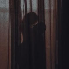 the shadow of a person standing in front of a curtain with their head on his hand