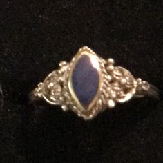 a gold ring with a blue stone in the center on a black cloth covered surface