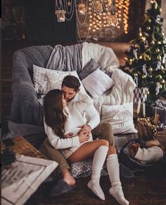 a man and woman sitting on a couch next to a christmas tree