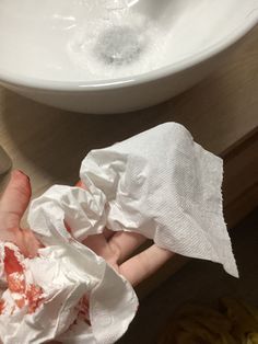 someone is holding some toilet paper in front of a sink with soapy water on it