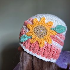 a close up of a doll wearing a crocheted hat with flowers on it