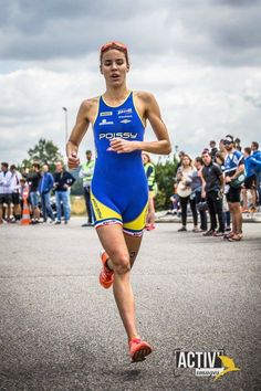 a woman in a blue and yellow swimsuit running down the street with people watching