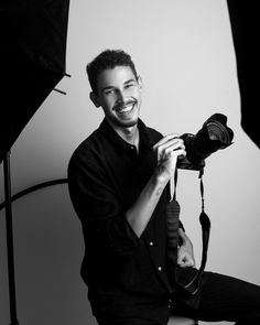 a black and white photo of a man holding a camera in front of a light