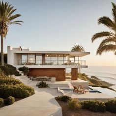 a modern house overlooking the ocean with palm trees