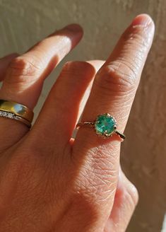 a woman's hand with two rings on it and an emerald stone in the middle