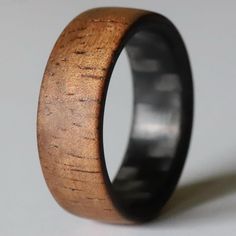 a wooden ring with black ceramic inlays on the outside, and wood grain inside